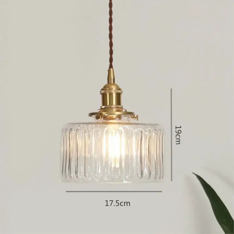A clear glass led pendant lamp with vertical ridges brass fixture and twisted brown cord for dining room use