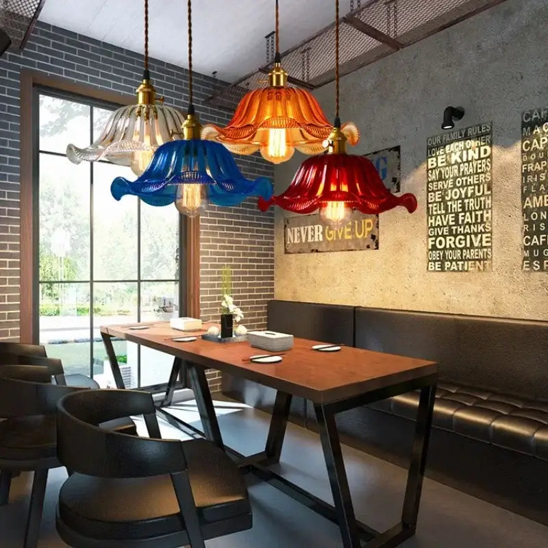 Vibrant multi-colored vintage hand blown glass pendant lights with brass accents hang above wooden dining table for cafe use