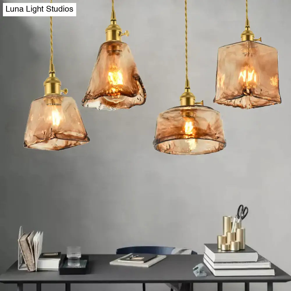 Four aubrey vintage handmade brass shaded pendant lights with tan glass hang above a desk in a modern interior