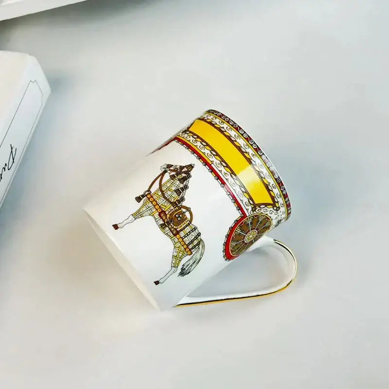 White ceramic mug cup featuring vintage horse and carriage illustration in gold with ornate borders for dining room use