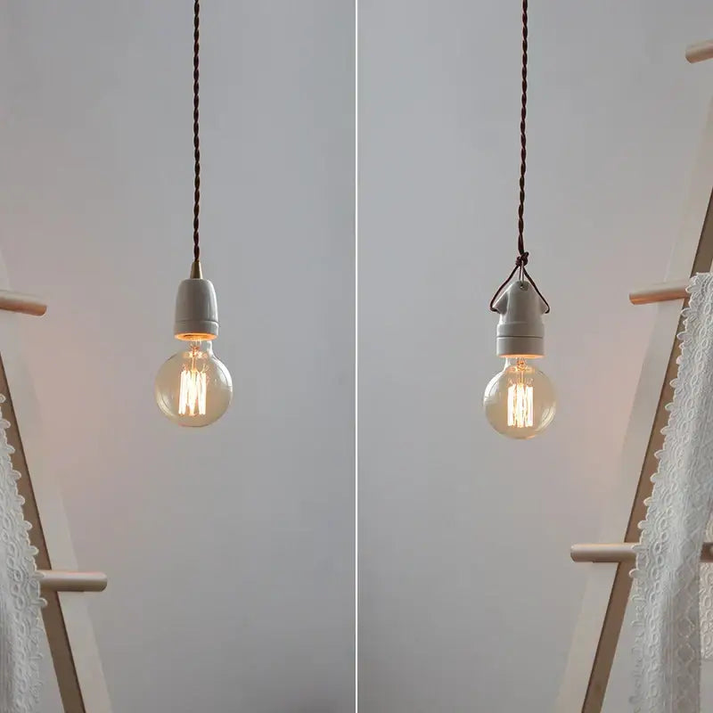 A warm-glowing vintage industrial matte white ceramic LED pendant lamp with clear glass bulb and dark braided cord