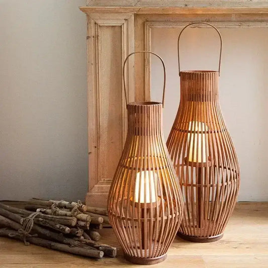 Two tall slender vintage natural bamboo lantern candle holders with warm wood slats and metal handles for living room decor