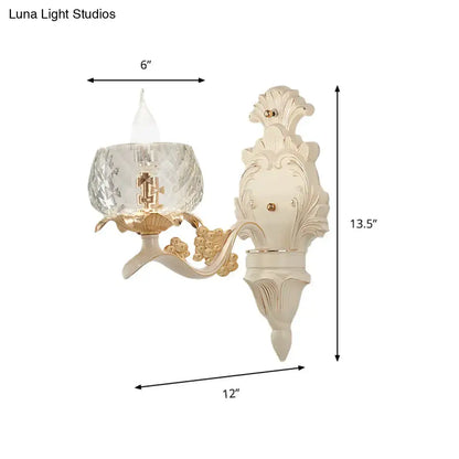 Cream-colored ornate wall light sconce with gold accents and faceted crystal glass shade for bedroom use