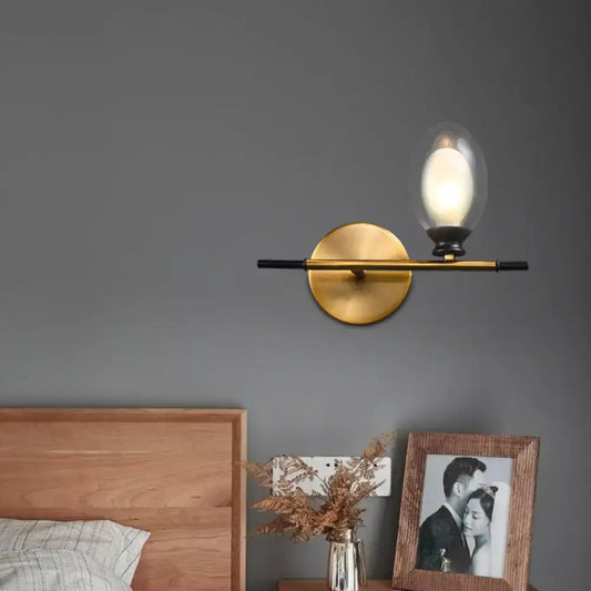 Vintage oval wall sconce brass and black with clear glass bulb designed for bedroom lighting