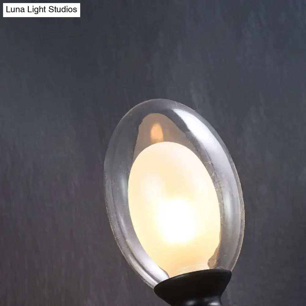 A vintage oval wall sconce with a warm glowing led bulb in a translucent glass shade and a sleek black base