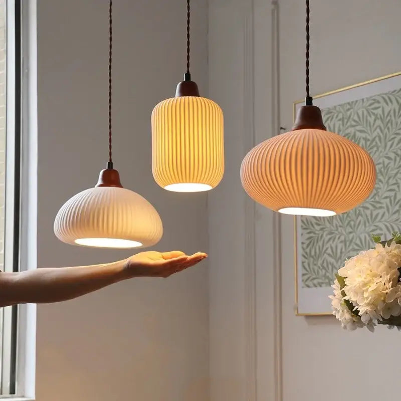 Three warm-toned ceramic wood led pendant lights with ribbed design hang from braided cords for dining room decorbites