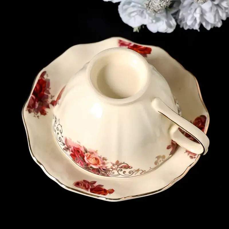 Vintage rose porcelain coffee mug in cream with red and pink floral patterns and gold trim on matching saucer