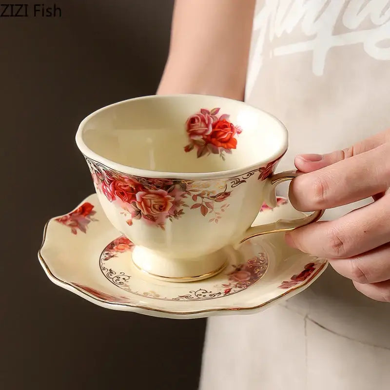 Cream-colored porcelain coffee mug and saucer set with delicate red rose patterns and golden edge for dining room use