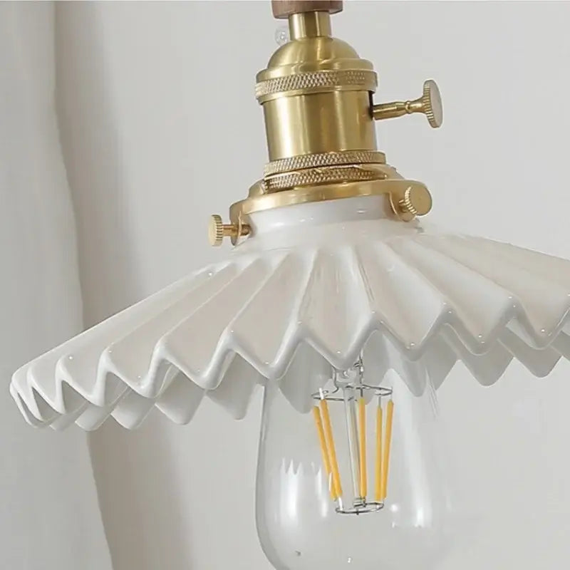 White ceramic pendant light fixture with brass socket and edison bulb featuring walnut wood for dining room use