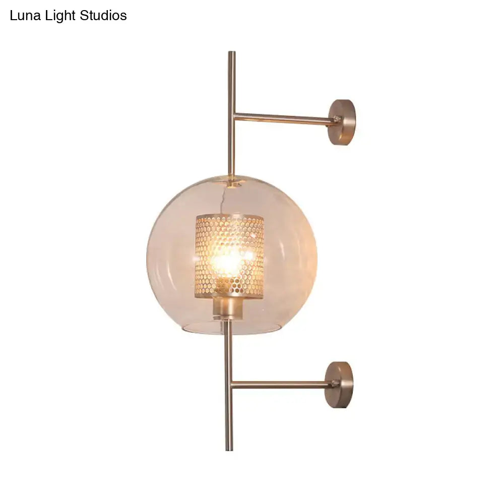 Modern brass-finished clear glass sconce light with a clear spherical shade and honeycomb metal diffuser for bedroom wall use