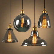 Set of four vintage pendant lights with amber glass shades and brass fixtures featuring exposed filament bulbs