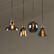 Set of four vintage-style pendant lights with smoked glass ball shades and brass accents for kitchen decorbites