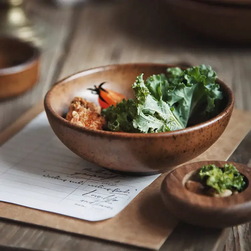 A rustic brown ceramic round swallow plate from decorbites filled with fresh kale and a cherry tomato