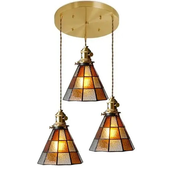 Brass-finished three-light glass copper pendant with amber frosted shades and wood knob switch for kitchen lighting
