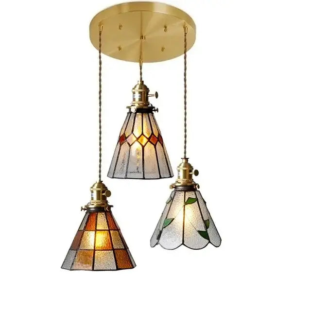 Brass-finished three-light glass copper pendant with amber green stained glass shades and wood knob switch for kitchen