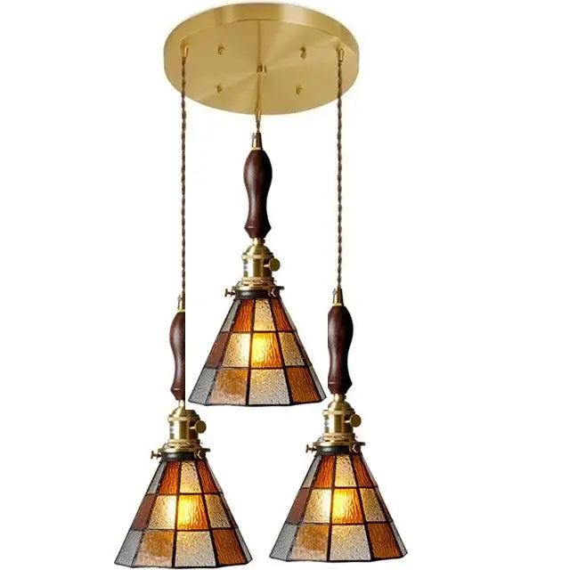 Brass-finished three-light glass copper pendant with amber frosted shades and wood knob switch for kitchen lighting