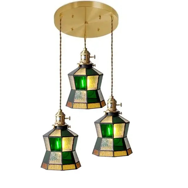 Brass-finished glass copper pendant light with three green and amber stained glass shades and wood knob switch for kitchen