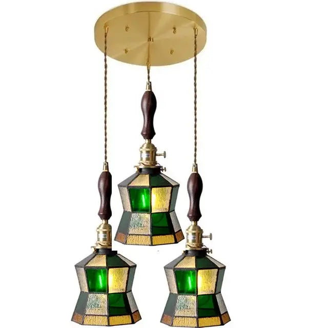 Brass-finished glass copper pendant light with three green and amber stained glass shades and wood knob switch for kitchen