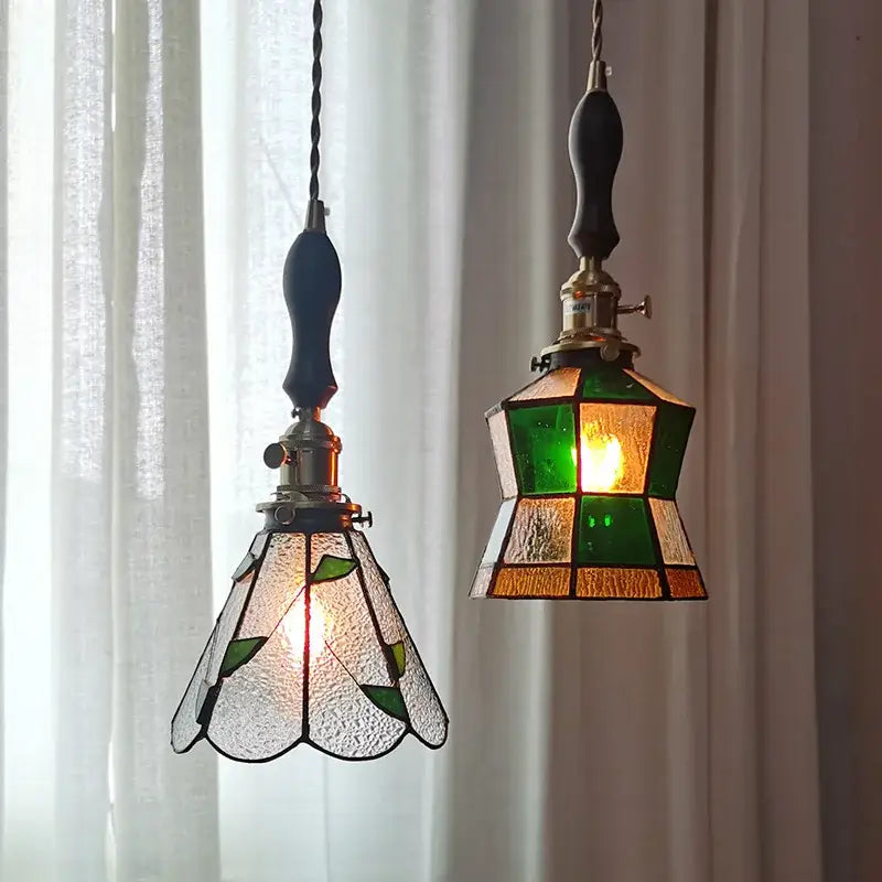 Two vintage stained glass copper pendant lights with green amber geometric and leaf designs featuring wood knob switch