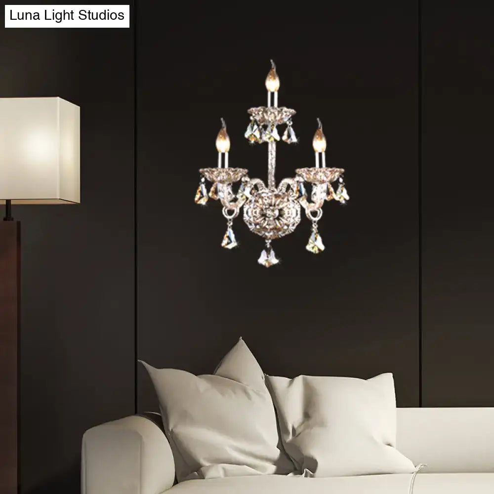 Vintage style wall light with ornate silver frame, three lit amber crystal candle bulbs, ideal for living room sconce