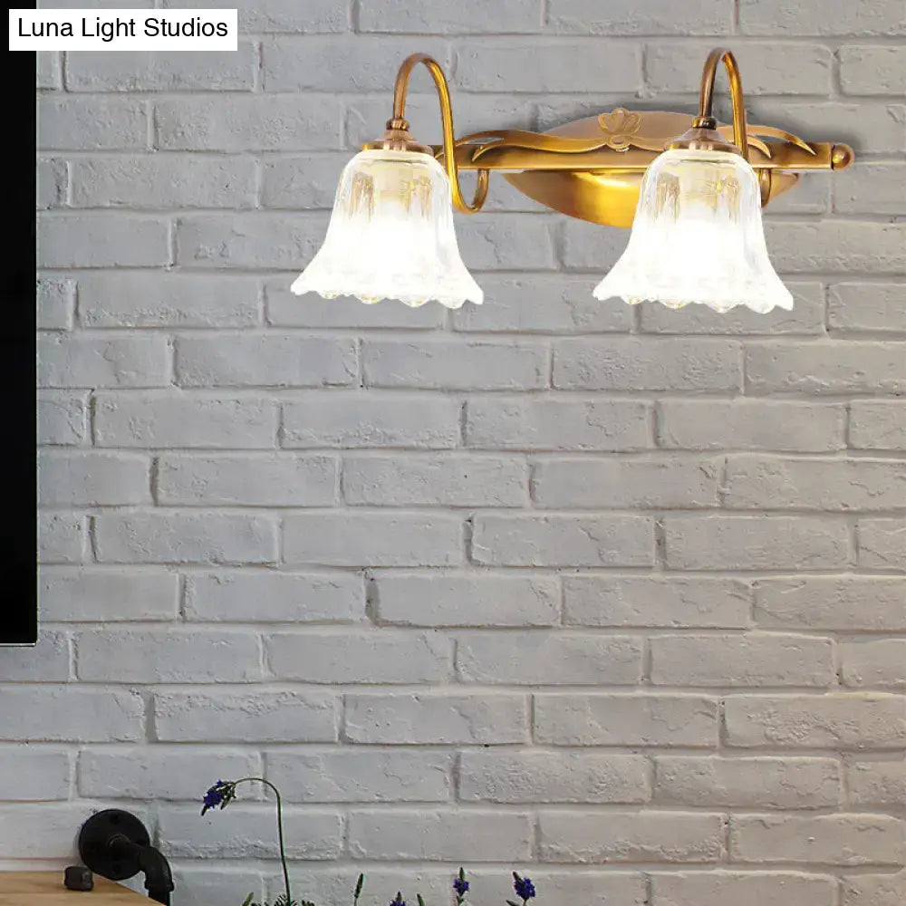 Vintage style wall light with brass finish and two frosted glass bell-shaped shades for bathroom vanity use