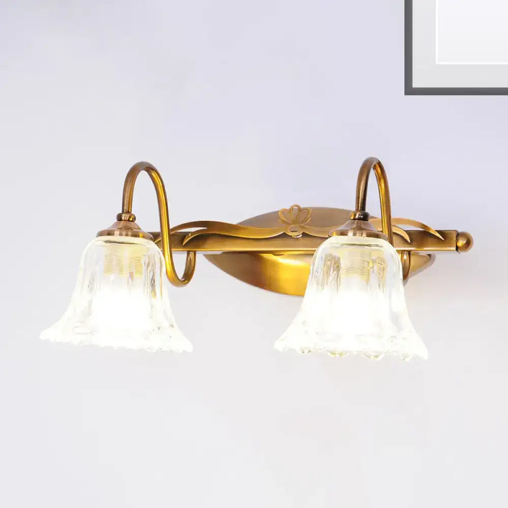 Vintage style antique brass wall light with two clear bell-shaped glass shades for bathroom vanity use