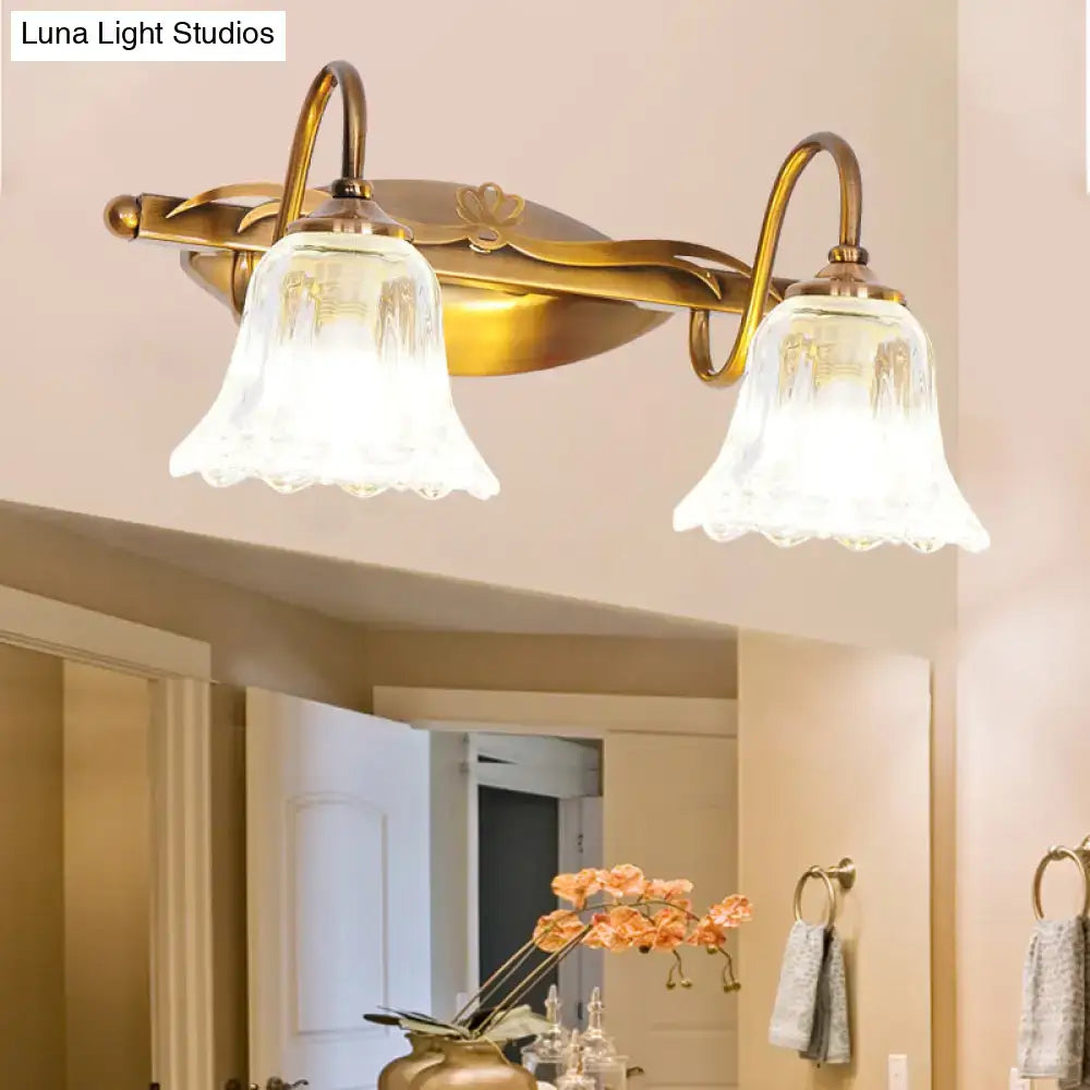 Vintage style antique brass wall light with two clear bell-shaped glass shades for bathroom vanity use