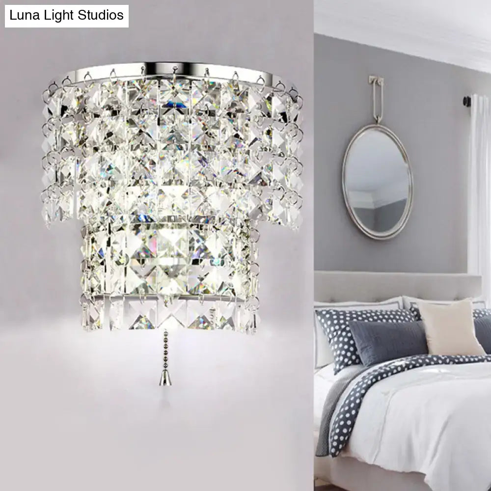 A vintage style wall sconce with a tiered crystal chandelier, sleek chrome frame, and faceted glass pieces