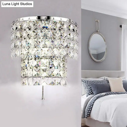 A vintage style wall sconce with a tiered crystal chandelier, sleek chrome frame, and faceted glass pieces