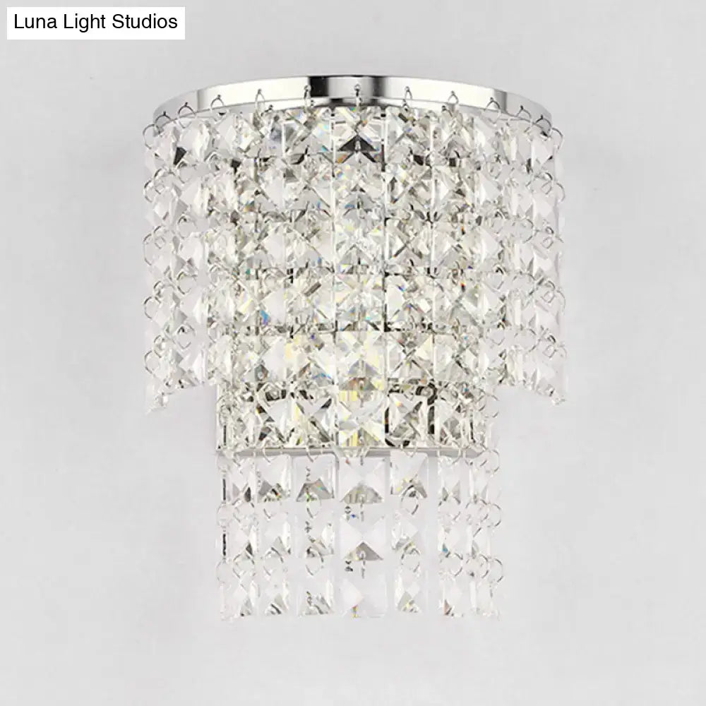 A vintage style wall sconce featuring a tiered crystal chandelier with a polished chrome frame and clear faceted crystals
