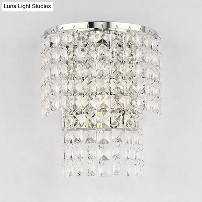 A vintage style wall sconce featuring a tiered crystal chandelier with a polished chrome frame and clear faceted crystals