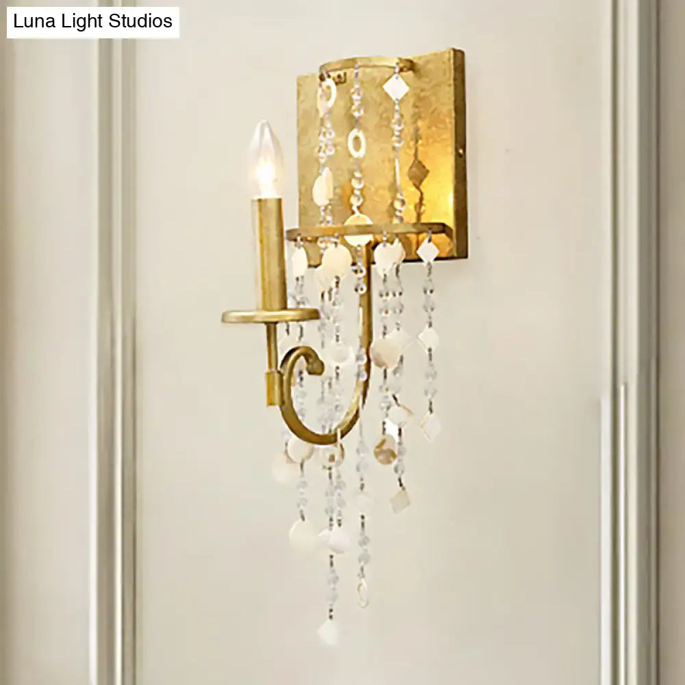 Vintage style gold wall sconce featuring a crystal beaded strand with clear and white cascading crystals for bedroom light