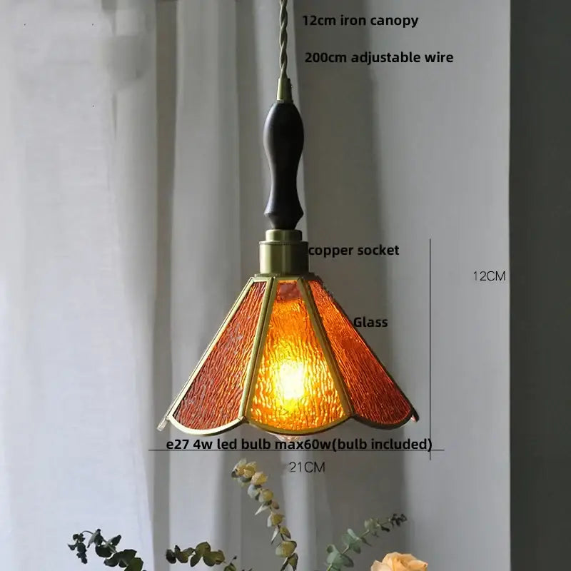 A warm amber pendant light with brass frame and dark wood handle contrasting decorbites blue glass led fixture