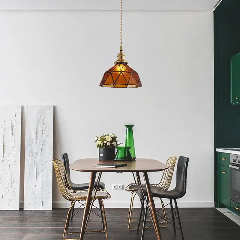 A warm amber stained glass pendant light with brass frame and chain hanging above a dining table decorbites blue glass