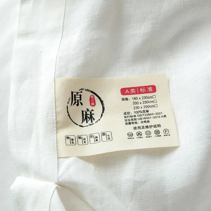 Beige fabric care label on vintage white and gray linen bedding set indicating 100 percent hemp material