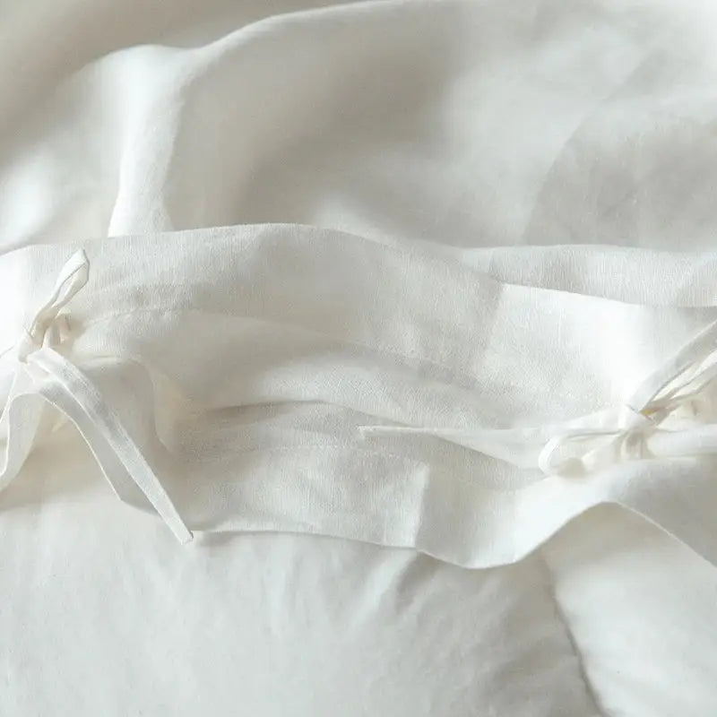 Soft off-white linen pillowcase with delicate folds and tie closures from vintage white and gray linen bedding set