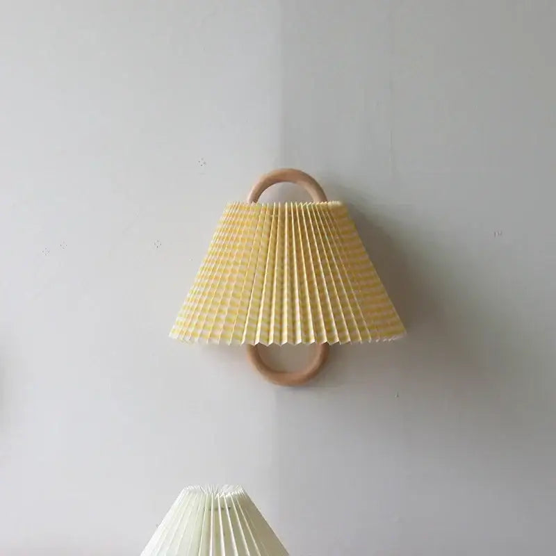 Wabi-sabi beech wood wall lamp with pale yellow pleated paper shade and natural wood ring handle for bedroom