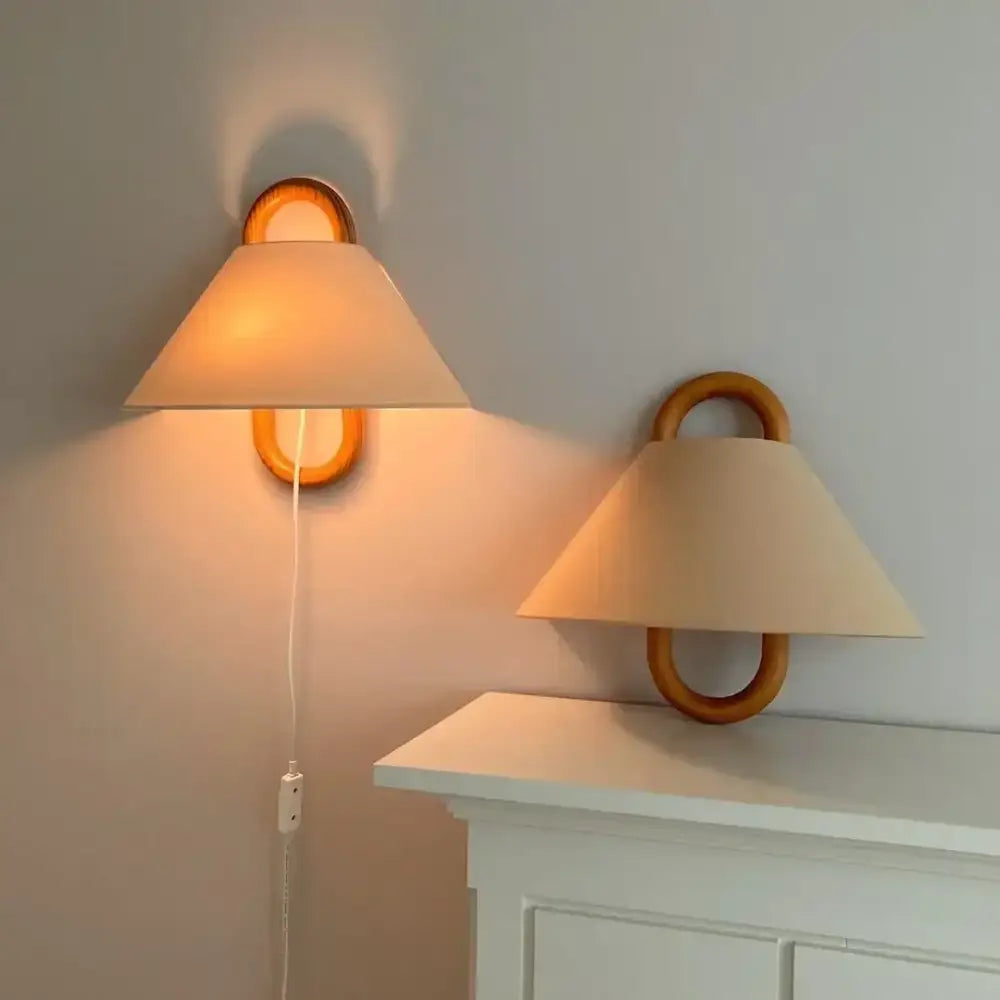 Warm-toned conical fabric shade wall lamp mounted on beech wood ring fixture for bedroom lighting