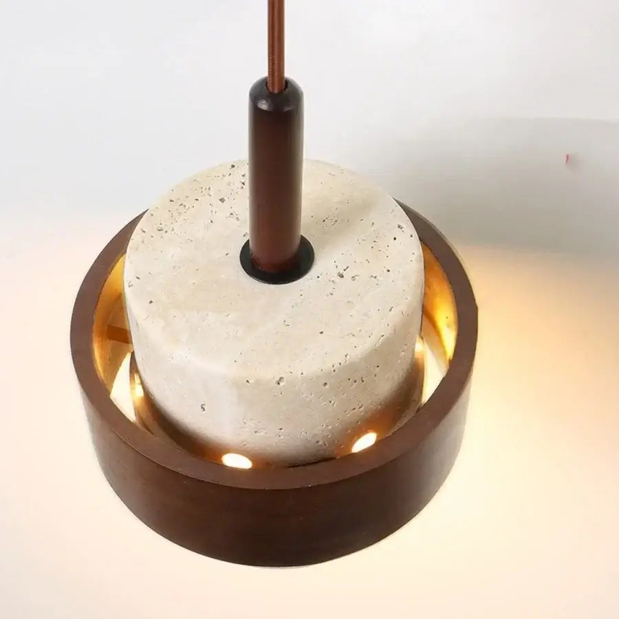 Wabi sabi beige and brown pendant light fixture with textured concrete disc and wooden ring illuminated by warm LEDs