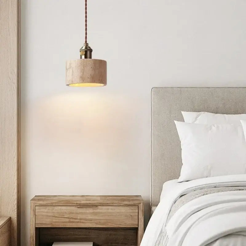 A beige cylindrical concrete pendant light with a warm glow and dark brown braided cord for dining room decorbites led yellow travertine