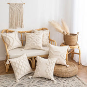 Cream-colored tufted cushion cover with tassel accents on a rattan sofa and floor for living room decor