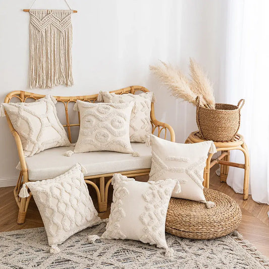 Cream-colored tufted cushion cover with tassel accents on a rattan sofa and floor for living room decor