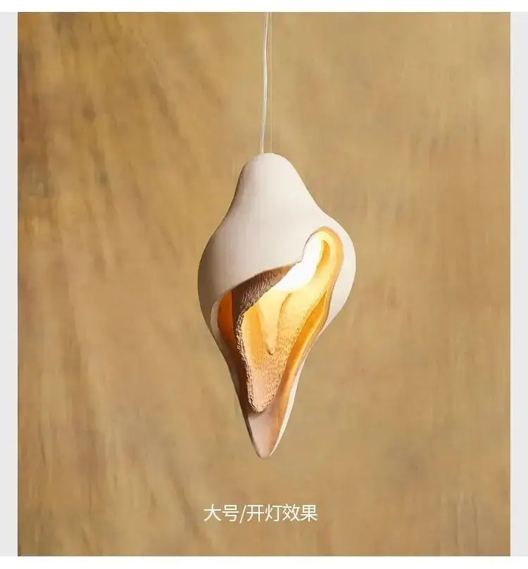 Wabi sabi cream gypsum conch pendant lamp featuring a sleek white ceramic shell design with warm golden glow interior