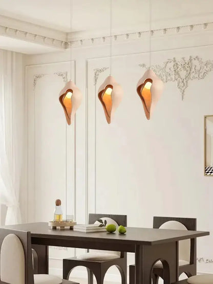 Three elegant peach-colored gypsum pendant lamps with shell design hanging in living room setting