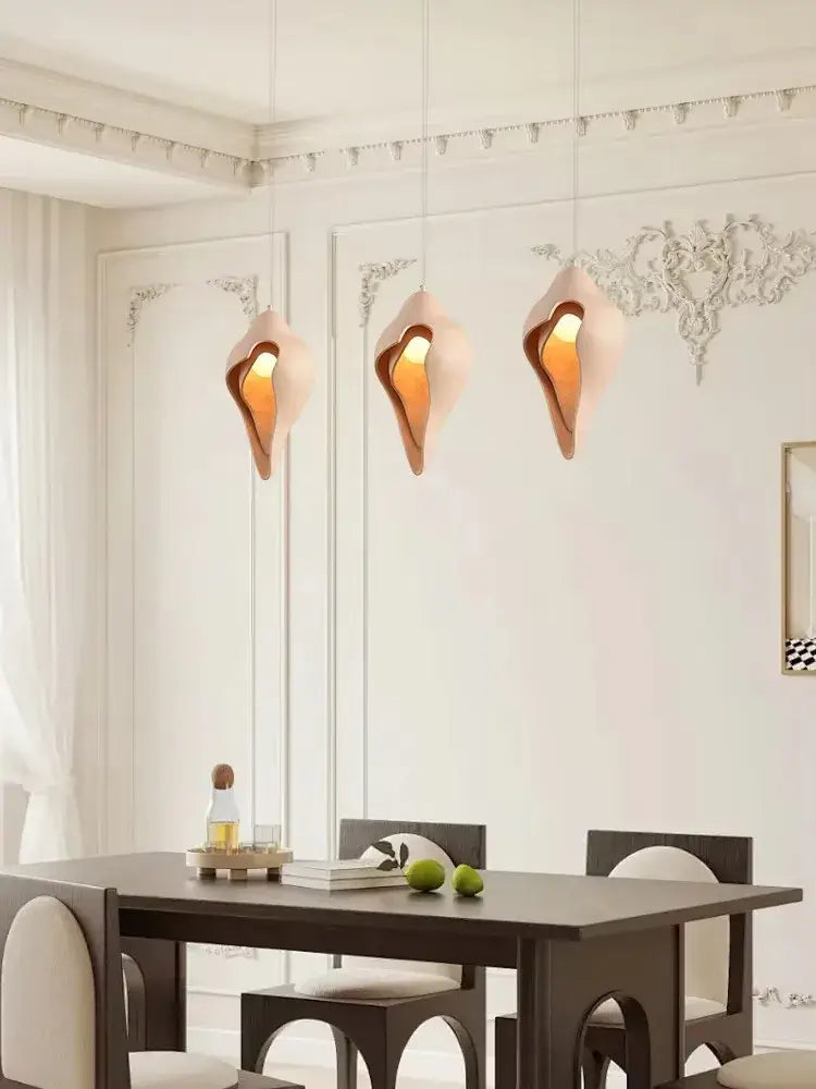Three elegant peach-colored gypsum pendant lamps with shell design hanging in living room setting