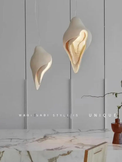 Two elegant off-white gypsum pendant lamps in shell design hang from the ceiling for living room use