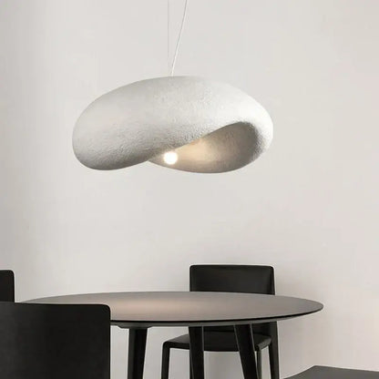 A cream style led pendant light with a cloud shape and textured surface hangs above the dining table decorbites cream style