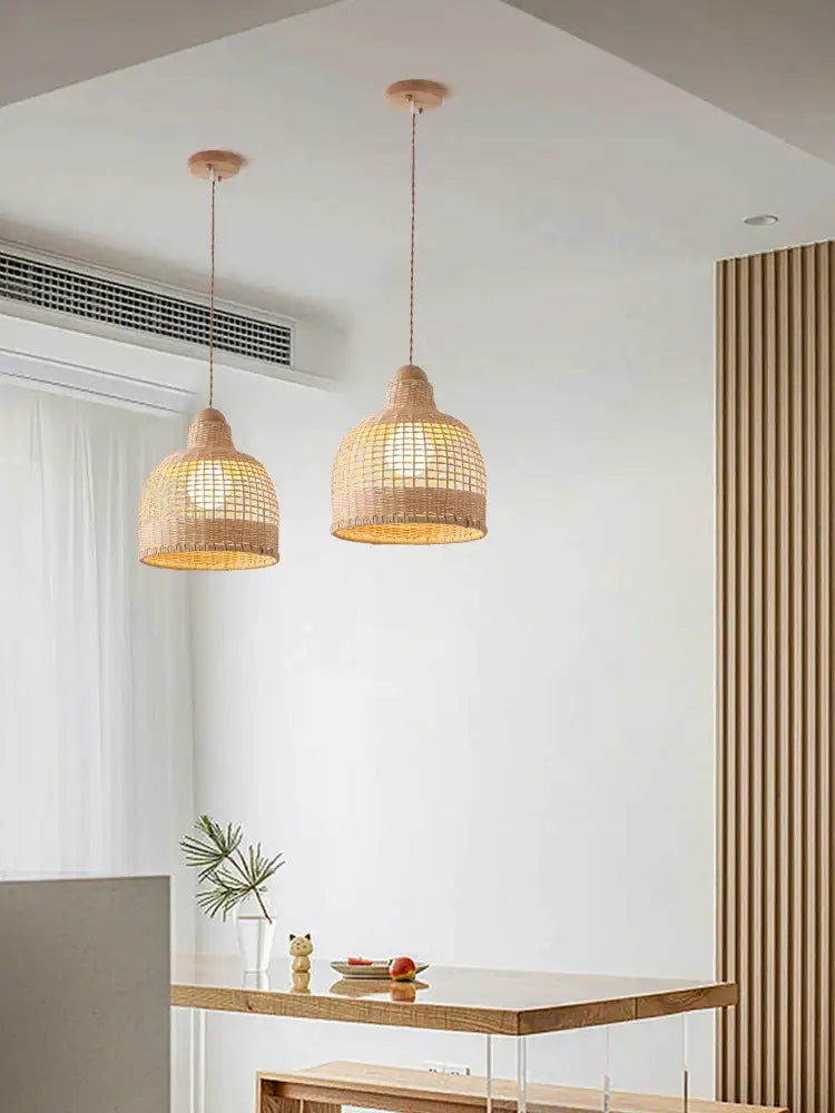 Two warm-toned woven rattan decorbites bamboo pendant lamps hanging over a dining room island