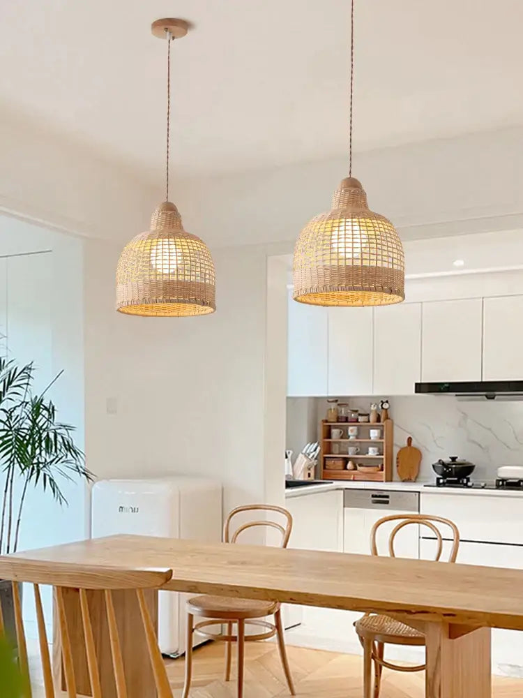 Two warm golden-brown decorbites bamboo pendant lamps woven from rattan hang over a dining room island
