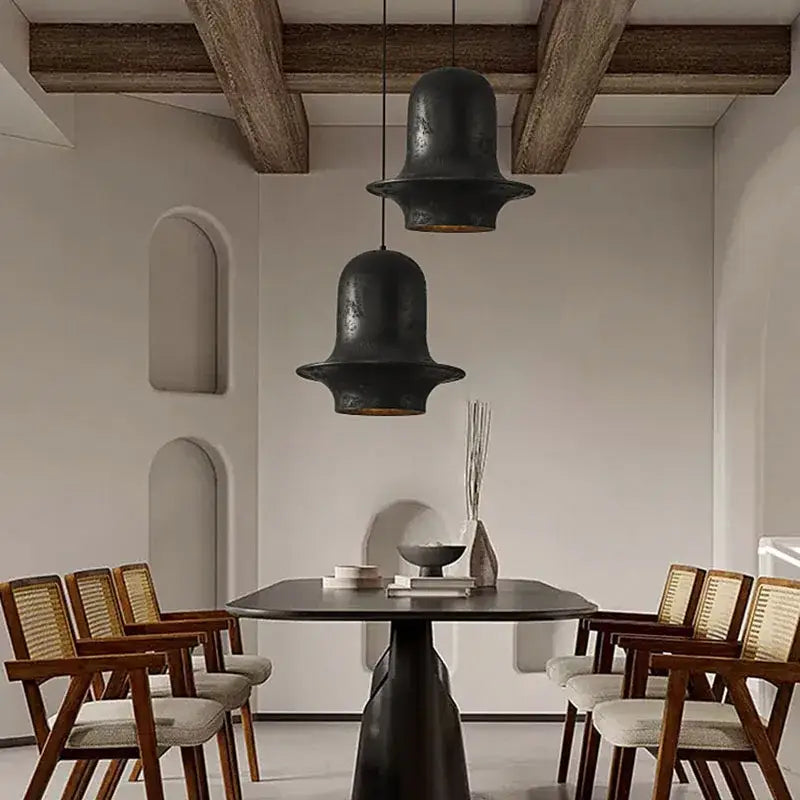 Two matte black bell-shaped pendant lights hang from the ceiling in the decorbites black wabi-sabi industrial chandelier design